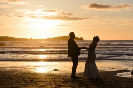 Bride and groom holding hands on beach at sunset - Picture by Stewart Girvan Photography