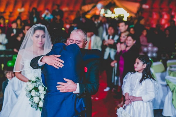 Bride's father hugging groom