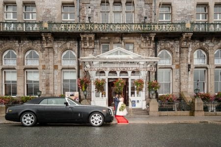 Bride and groom outside entrance of The Duke of Cornwall Hotel