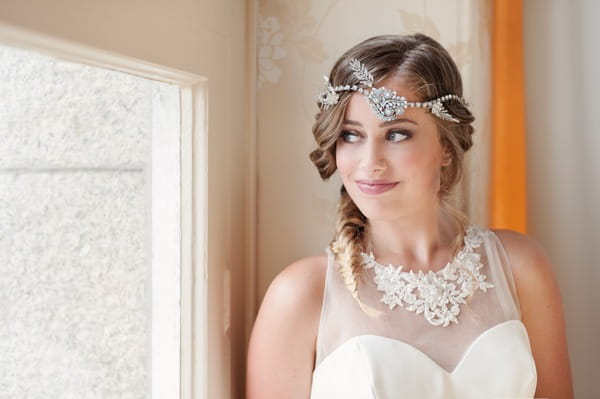 Bride with boho headband and large necklace looking out of window