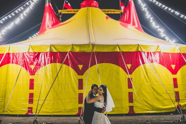 Bride and groom in front of circus tent