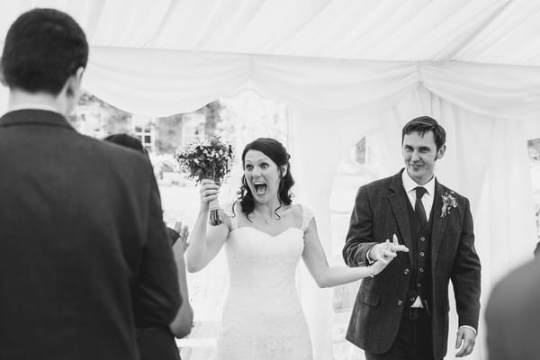 Happy bride and groom enter wedding breakfast in marquee