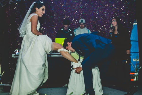 Groom taking of bride's garter with teeth