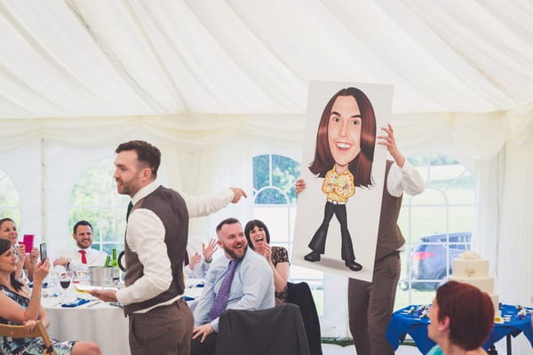 Best men holding caricature of groom