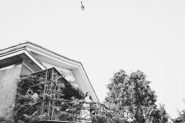 Bride throwing bouquet from balcony