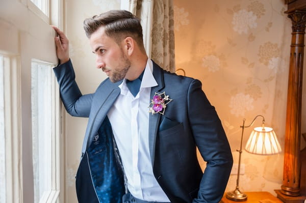 Groom in blue suit looking out of window