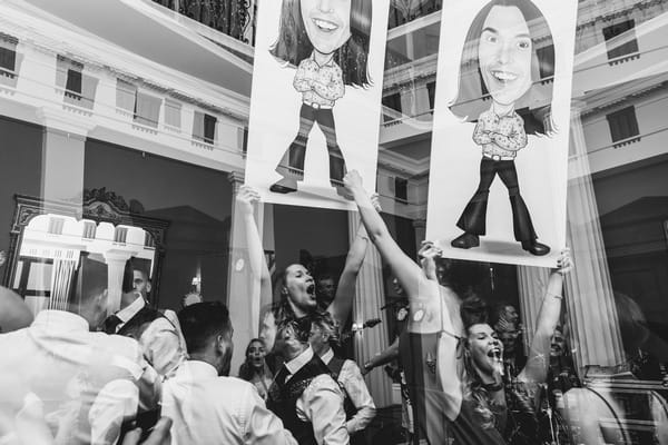 Wedding guests holding up caricatures of bride and groom