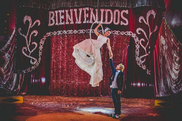 Groom holding bride's hand on trapeze