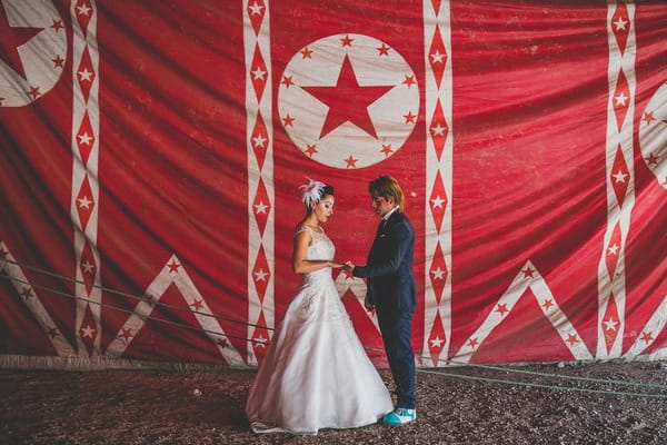 Bride and groom in front of red circus curtain