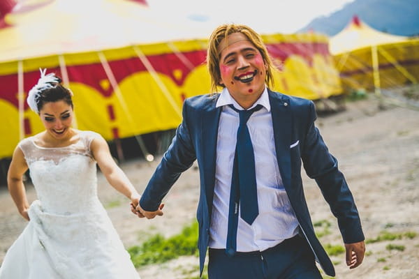 Groom with clown face leading bride by the hand