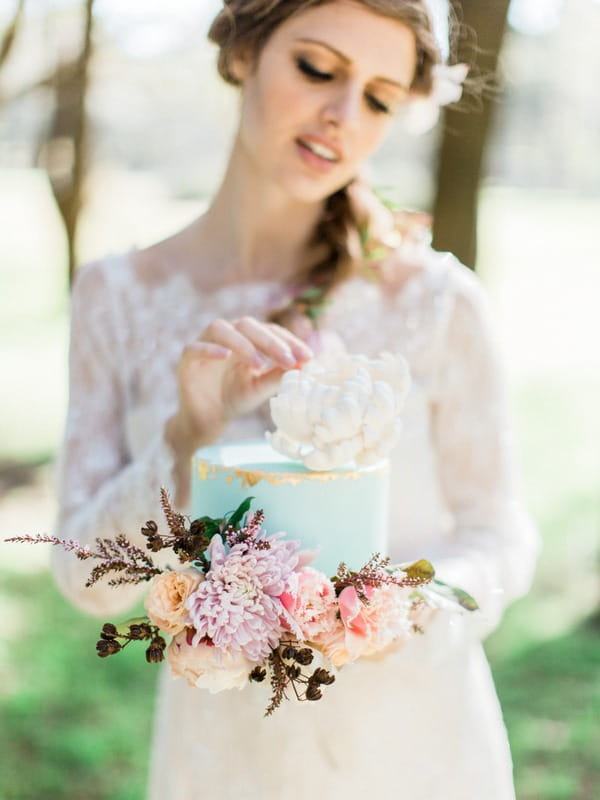 Bohemian bride holding blue wedding cake