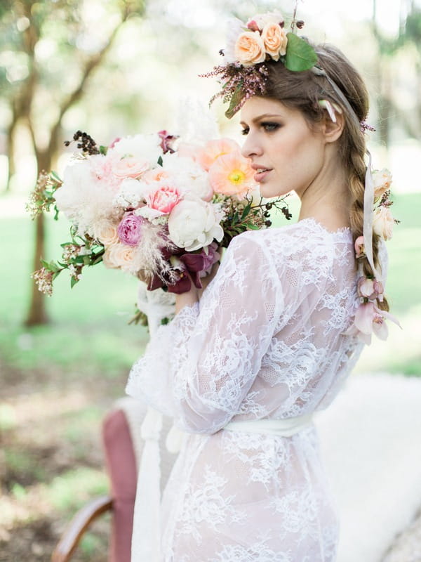 Bohemian bride in lace wedding robe holding bouquet