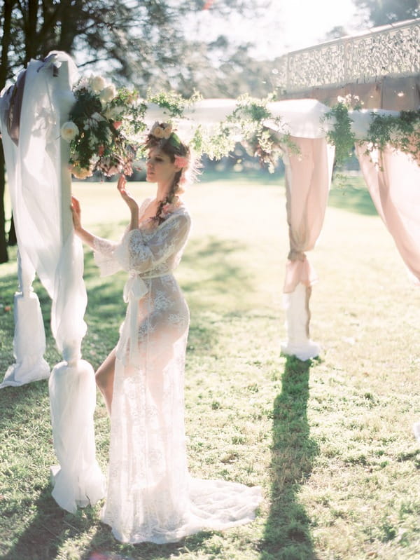 Bohemian bride looking at flowers on ceremony structure