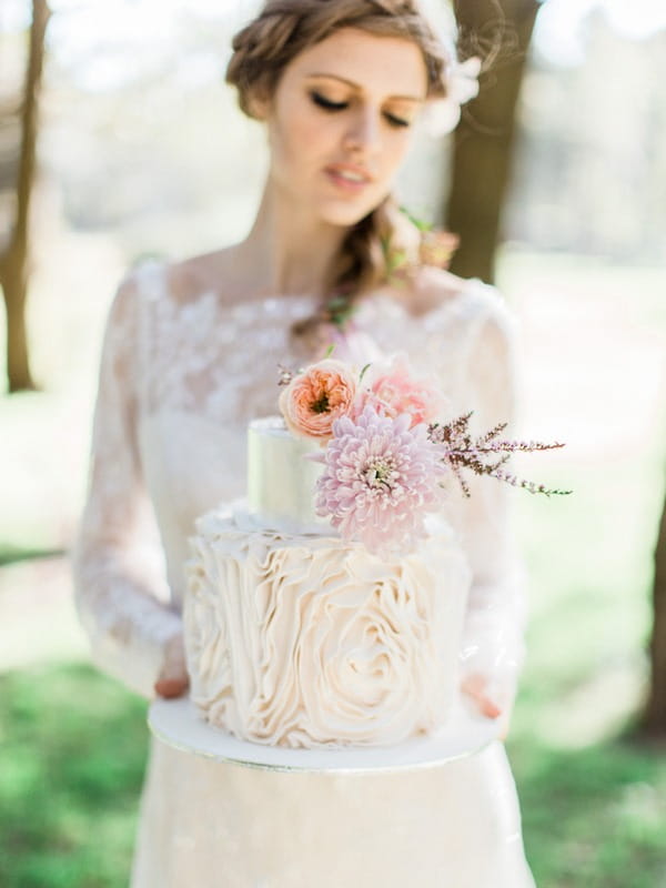 Bohemian bride holding wedding cake with frill icing