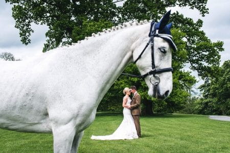 Horse with bride and groom in background under head - Picture by French Connection Photography