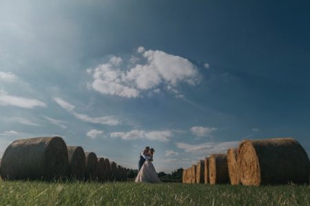 Bride and groom kissing in middle of large round hay bales - Picture by Emma and Rich