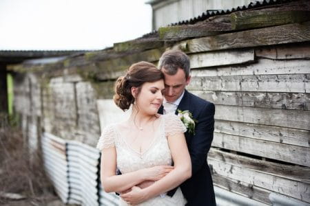 Groom standing behind bride with arms around her waist