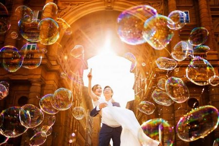 Groom carrying bride as she points at bubbles floating in the air - Picture by Fabio Mirulla Photographer