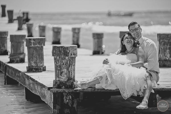 Bride and groom sitting on jetty