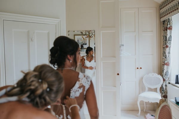 Bridesmaid doing up back of bride's wedding dress