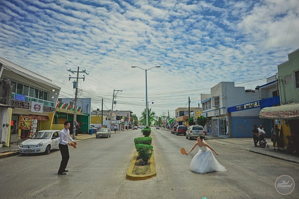 Bride and groom playing tennis in middle of street in Mexico