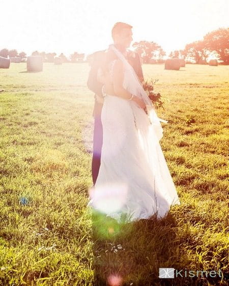 Bride and groom standing in hazy sunshine - Picture by Kismet Photography