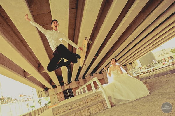 Groom jumping off skateboard as bride watches