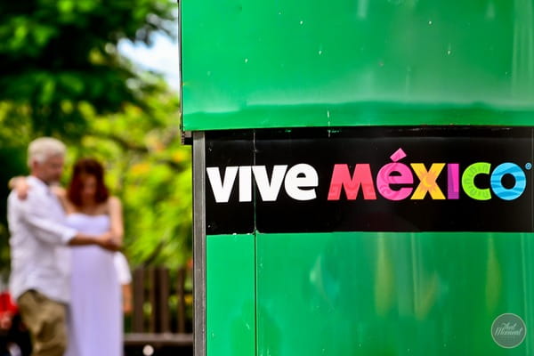 Bride and groom next to vive Mexico sign