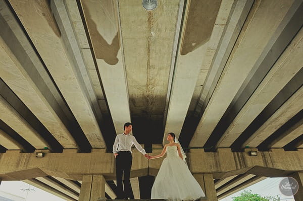 Bride and groom holding hands under bridge