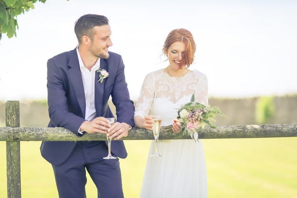 Bride and groom leaning on fence