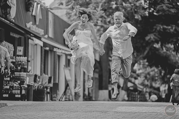 Bride and groom jumping in street