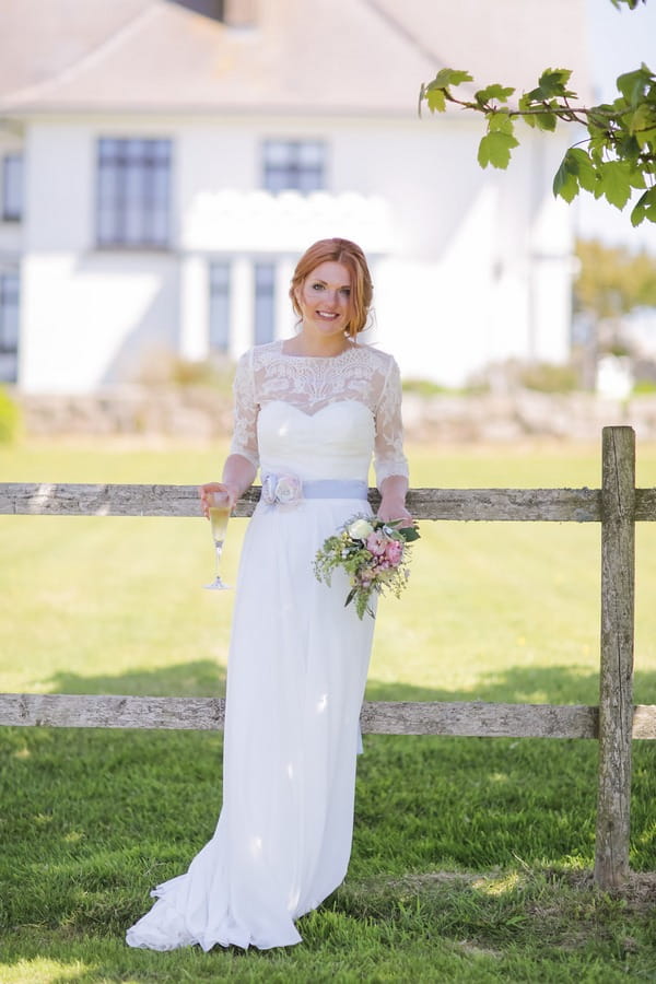 Bride leaning against fence