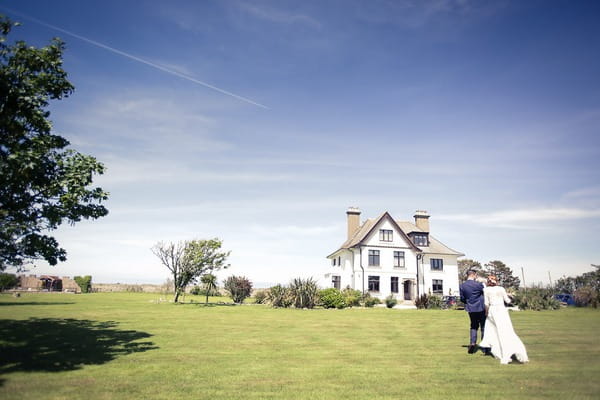 Bride and groom walking across grounds of BoHo Cornwall