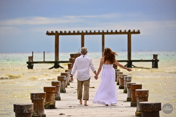 Bride and groom walking on beach holding hands