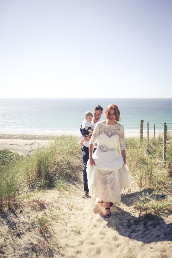 Bride and groom walking along beach path in Cornwall