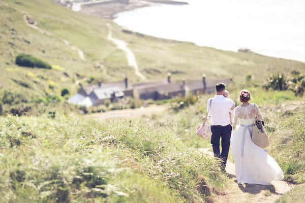 Bride and groom walking back from beach in Cornwall