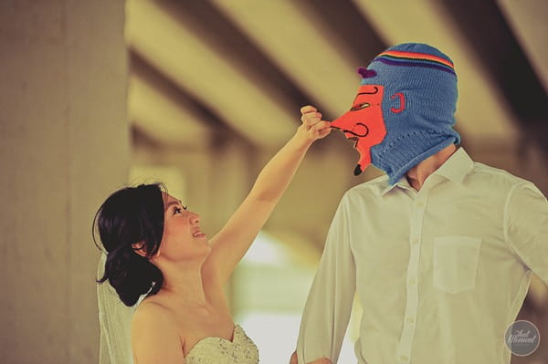 Bride pulling nose of groom's devil balaclava