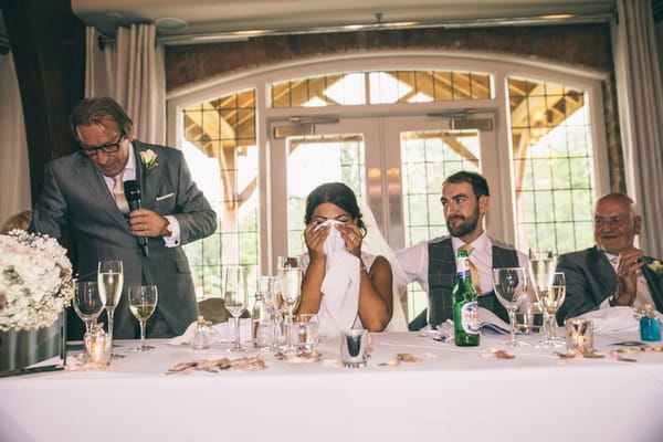 Bride hiding face with napkin during father of the bride wedding speech