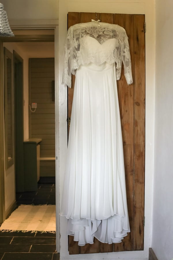 Lace wedding dress hanging on door