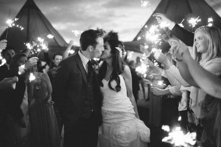 Bride and groom kissing surrounded by guests with sparklers - Picture by Frances Sales Photography