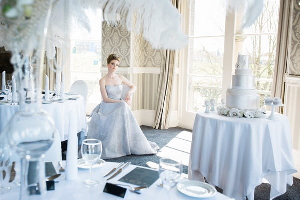 Bride sitting amongst wedding tables in The Duke of Cornwall Hotel