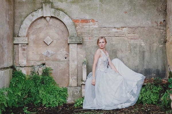 Bride sitting by old fountain