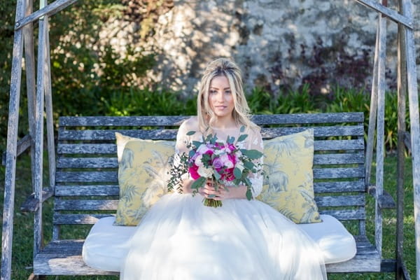 Bride sitting on bench holding bouquet