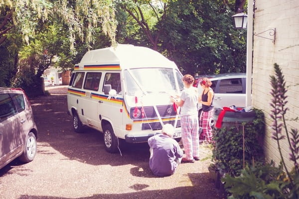 Guests putting ribbons on wedding camper van