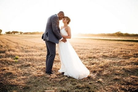 Bride and groom touching heads in a field - Picture by Suzi Photography