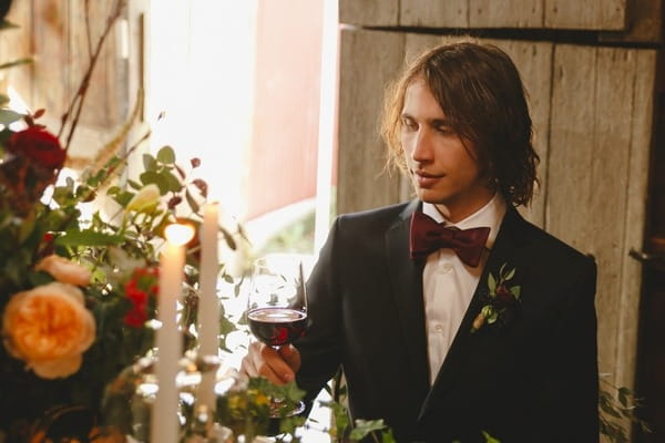 Groom holding glass of red wine