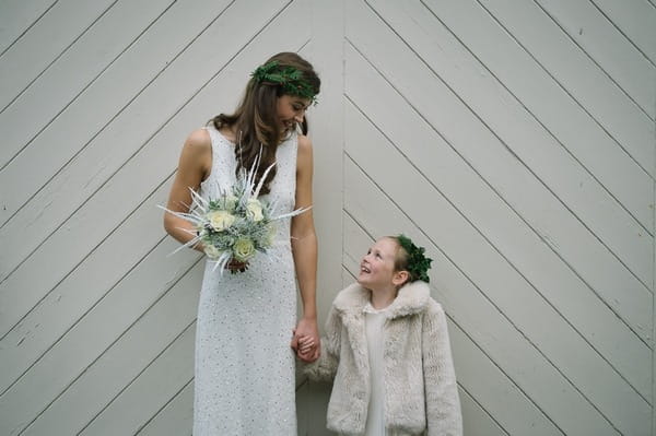 Bride and flower girl holding hands and looking at each other