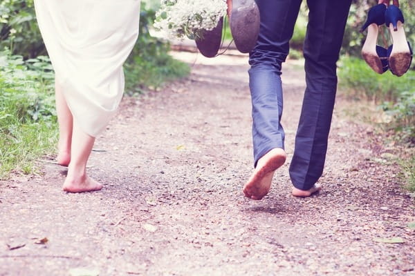 Bride and groom walking barefoot down path