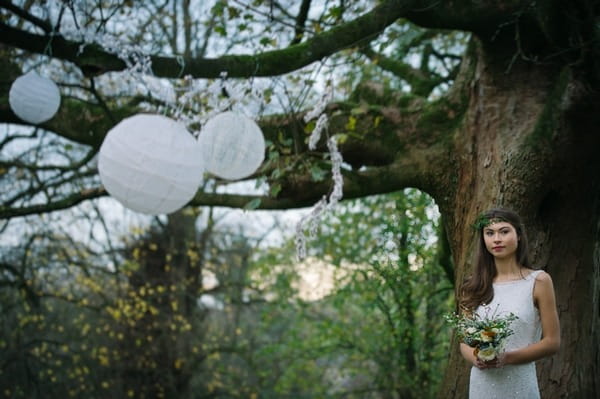 Bride standing by tree with hanging lanterns