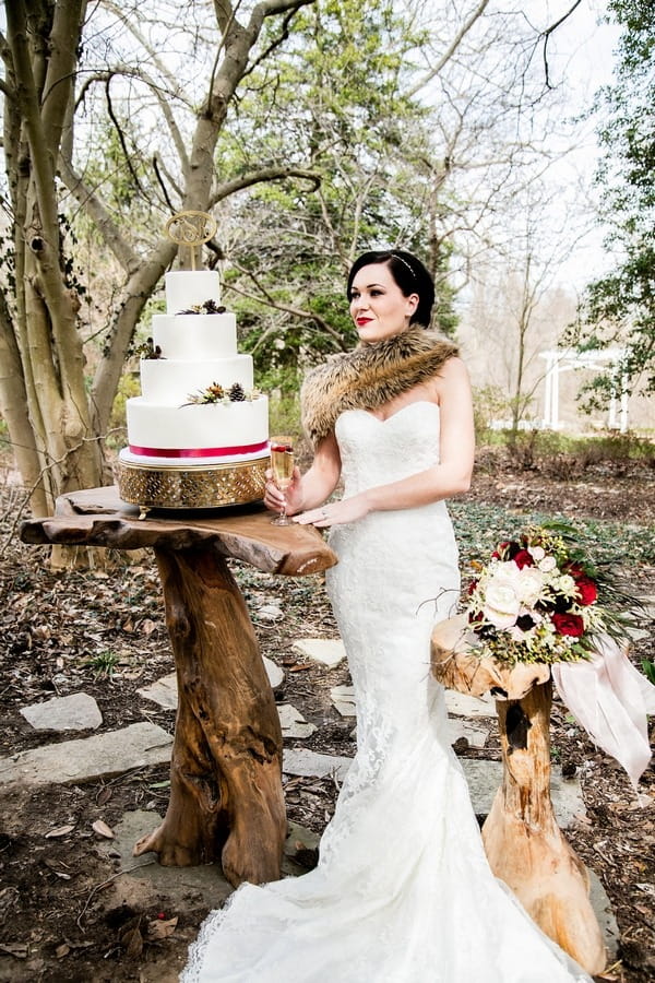 Bride wearing shrug standing next to of wedding cake